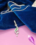 A silver pendant shaped like a stylized musical note with a small green stone accent.