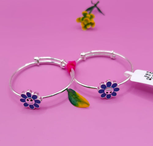 Two silver adjustable bangles with colorful flower charms, displayed on a pink background with a small yellow flower prop and a white price tag.