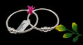 Two silver beaded bracelets with polished ball spacers, shown on a light gray background with a small pink feather accent and a green leaf prop.