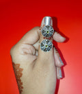 silver toe rings with intricate black and white geometric patterns and small green stones