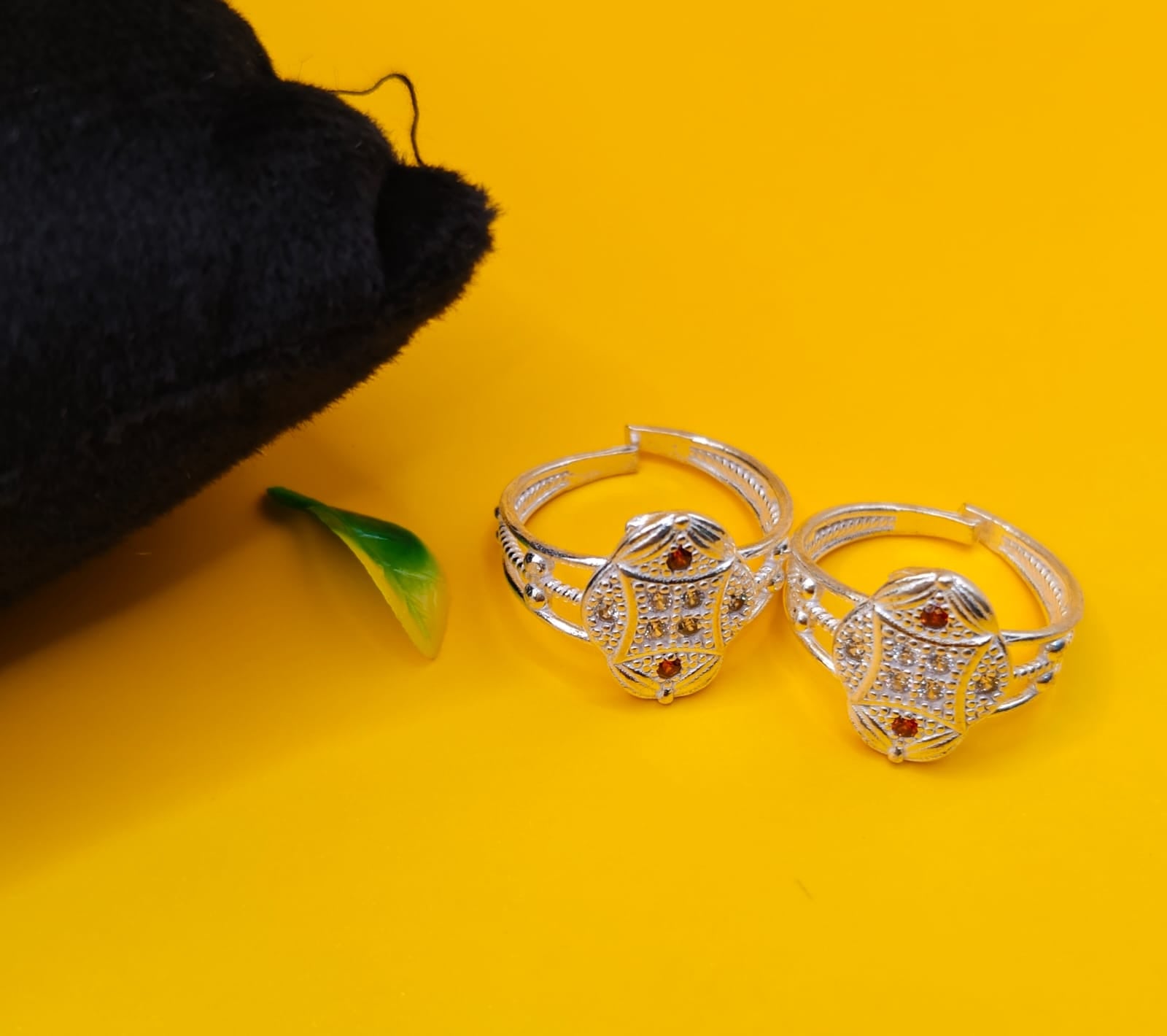 silver toe rings with intricate filigree detailing and small red stone accents