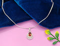 A silver teardrop pendant necklace with a faceted orange-red gemstone.