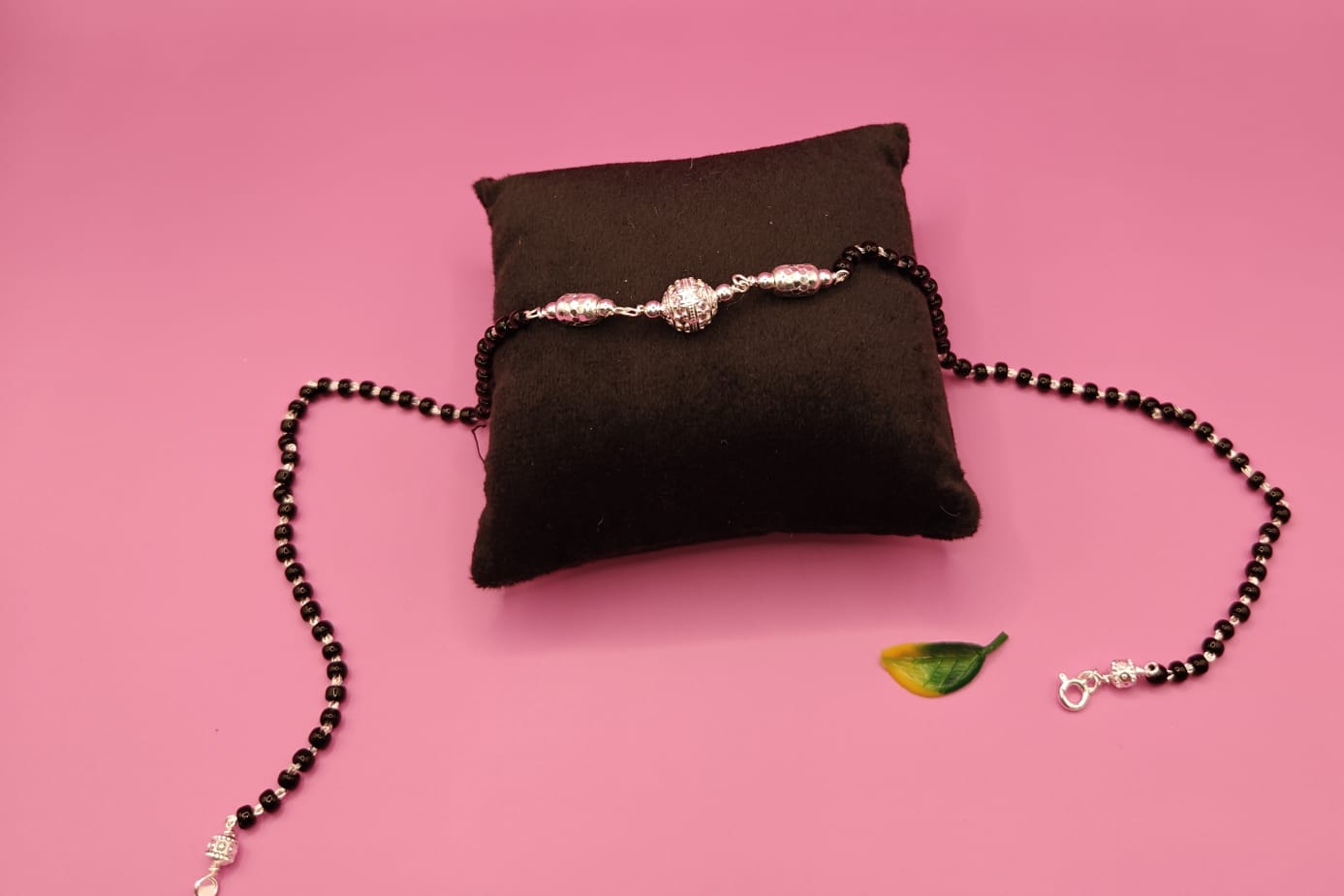 A beaded necklace with black beads and silver-toned metal details.