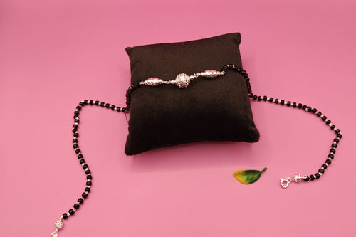 A beaded necklace with black beads and silver-toned metal details.