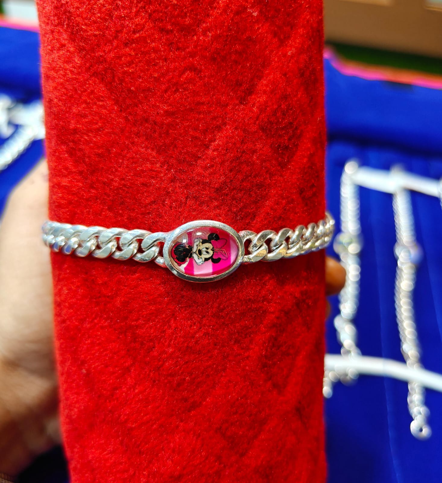 silver chain bracelet with a round pink charm featuring a black Mickey Mouse