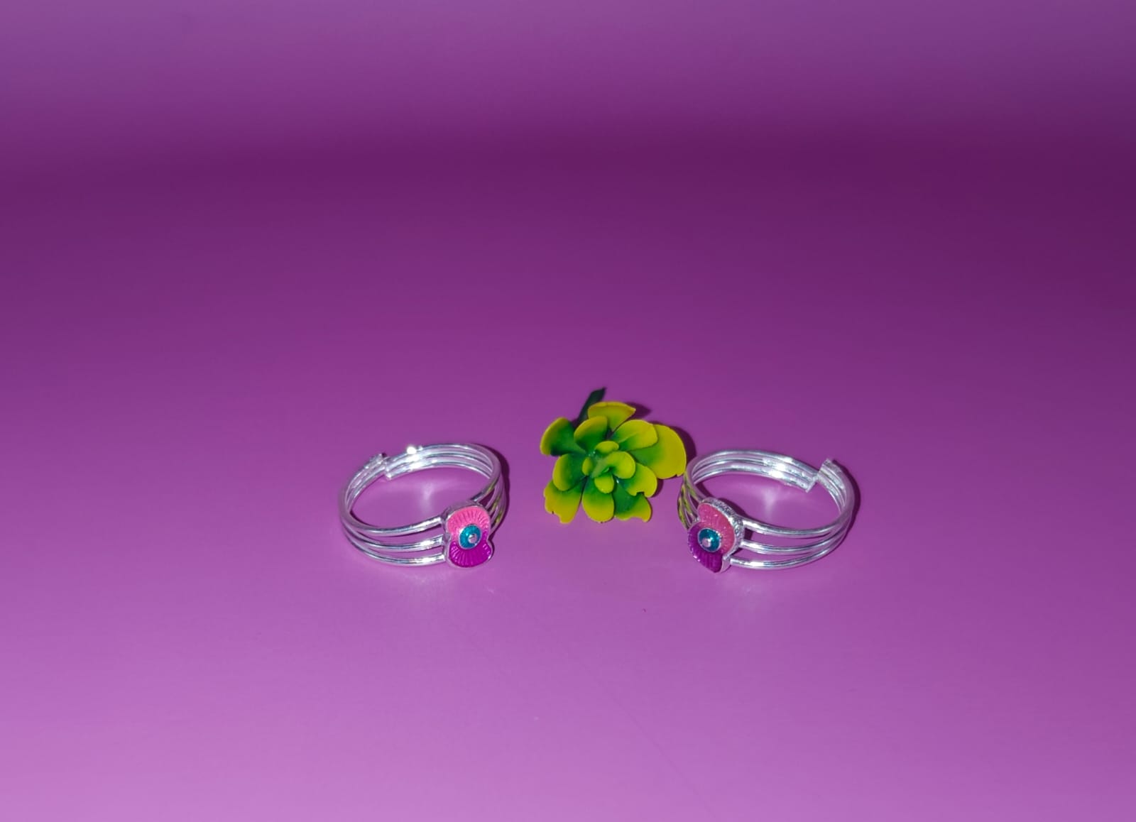Two silver-toned toe rings with small colorful gemstone accents